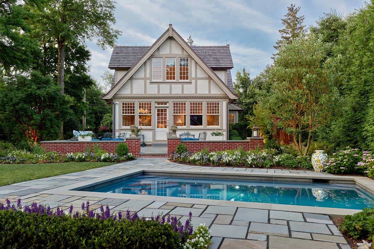 Guest cottage with steep gable and multi-pane windows, viewed across the swimming pool
