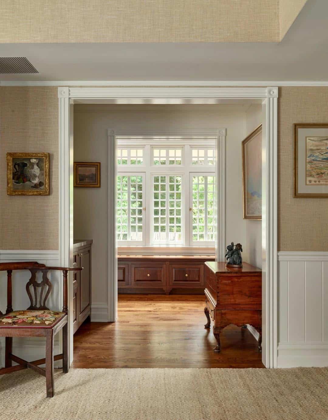 Hallway view through an arched doorway into a room with a built-in window seat
