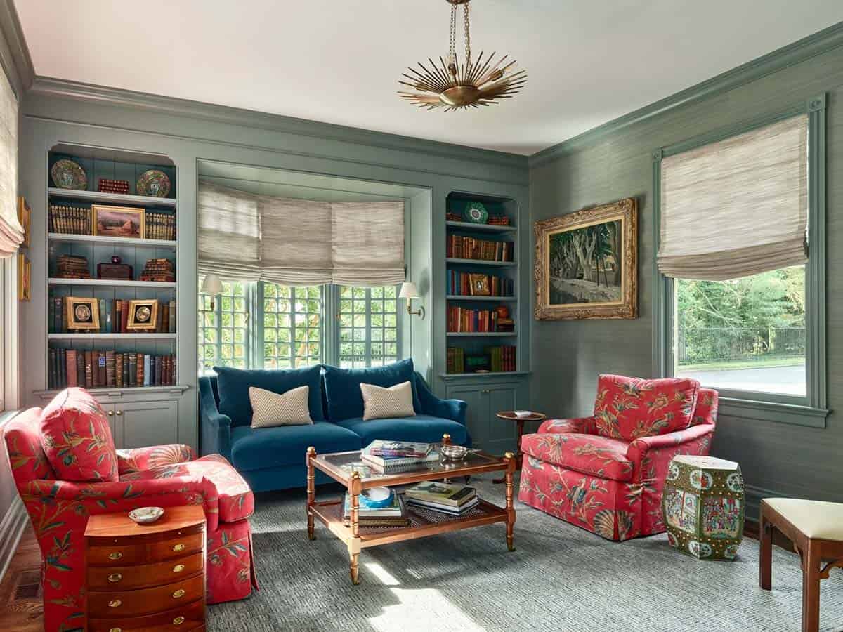Sitting room with sage-green walls, red floral armchairs, and a starburst chandelier