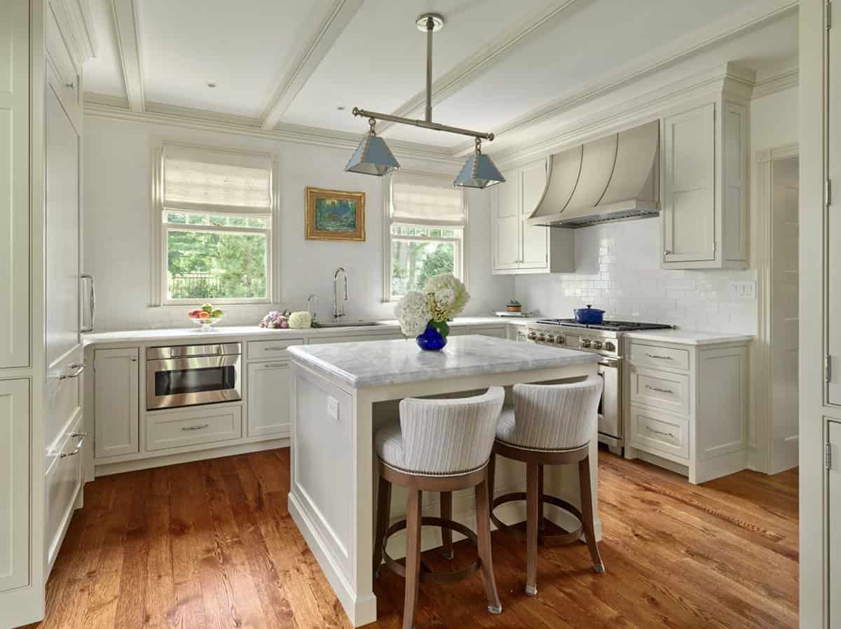 White kitchen with marble-topped island, subway tile backsplash, and wood floors