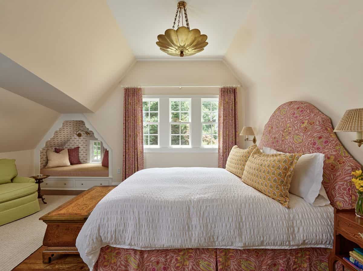 Bedroom with patterned floral headboard, built-in window nook, and gold pendant light