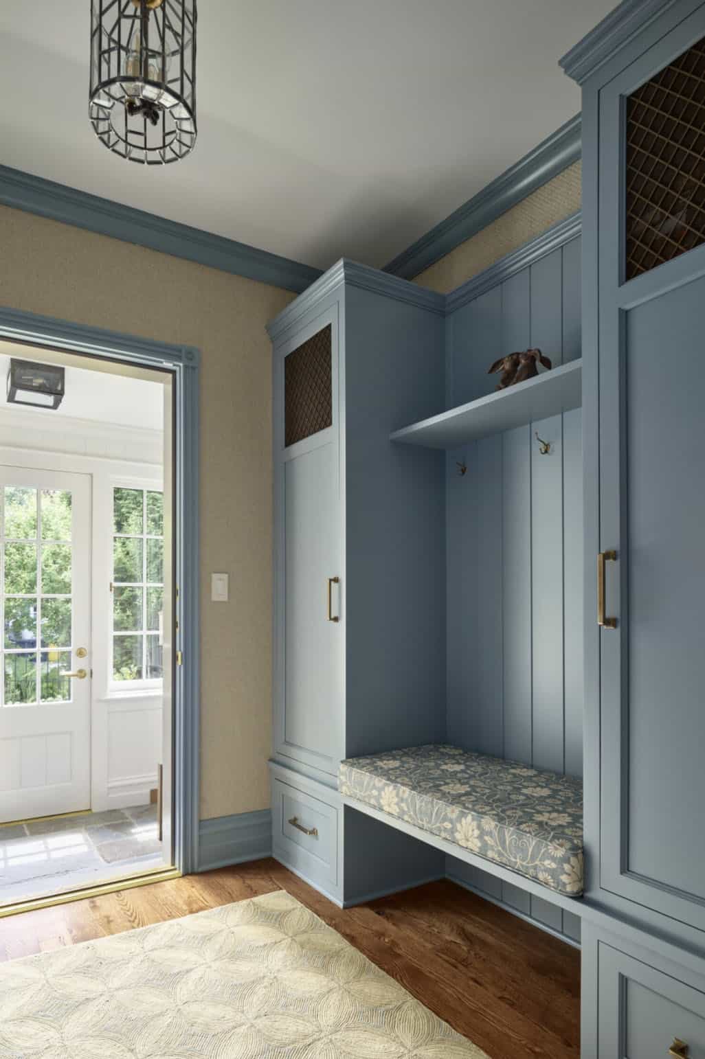  Mudroom with blue built-in cabinetry, upholstered bench seat, and patterned rug