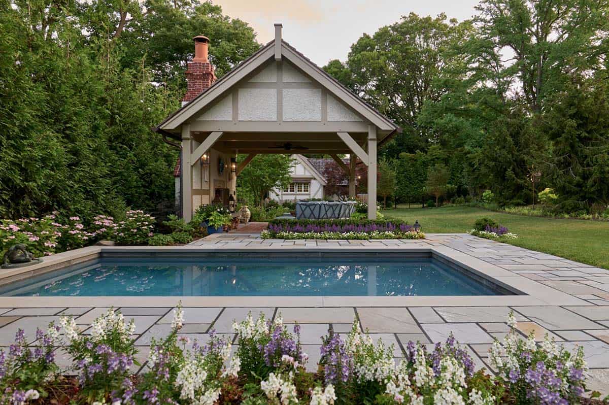 Twilight view of the pool and timber pavilion with flowering plants along the patio edge
