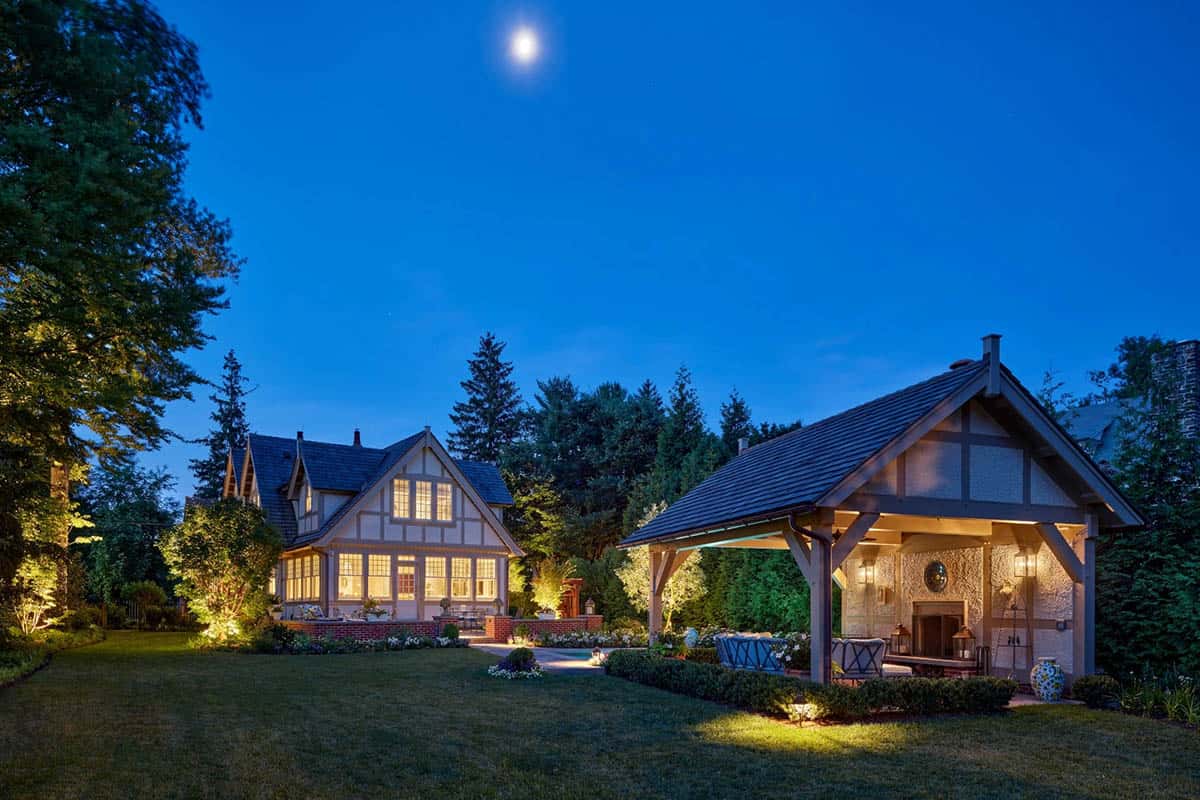 Nighttime view of the main house and pool pavilion glowing under landscape lighting