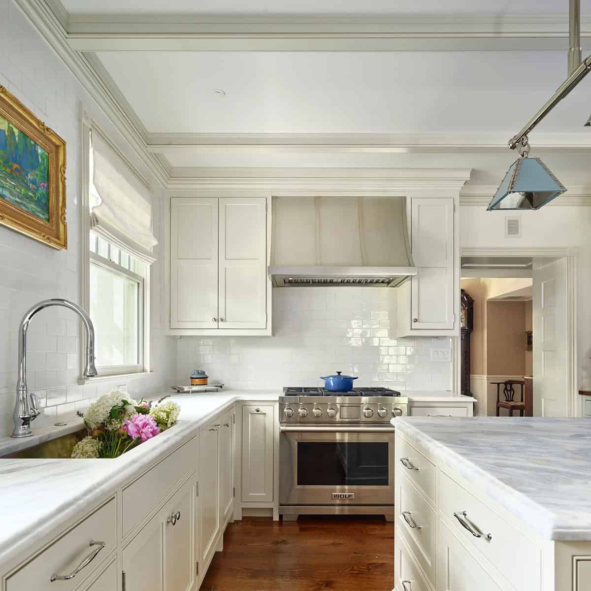 White kitchen with subway tile, marble counters, stainless range, and blue pendant light