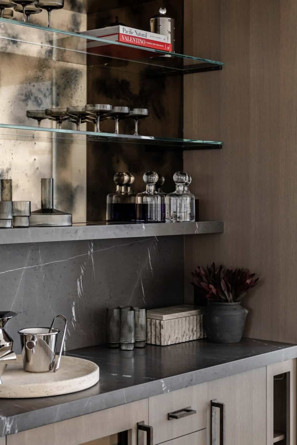 Bar shelving detail with decanters, glassware, and antique mirror backdrop