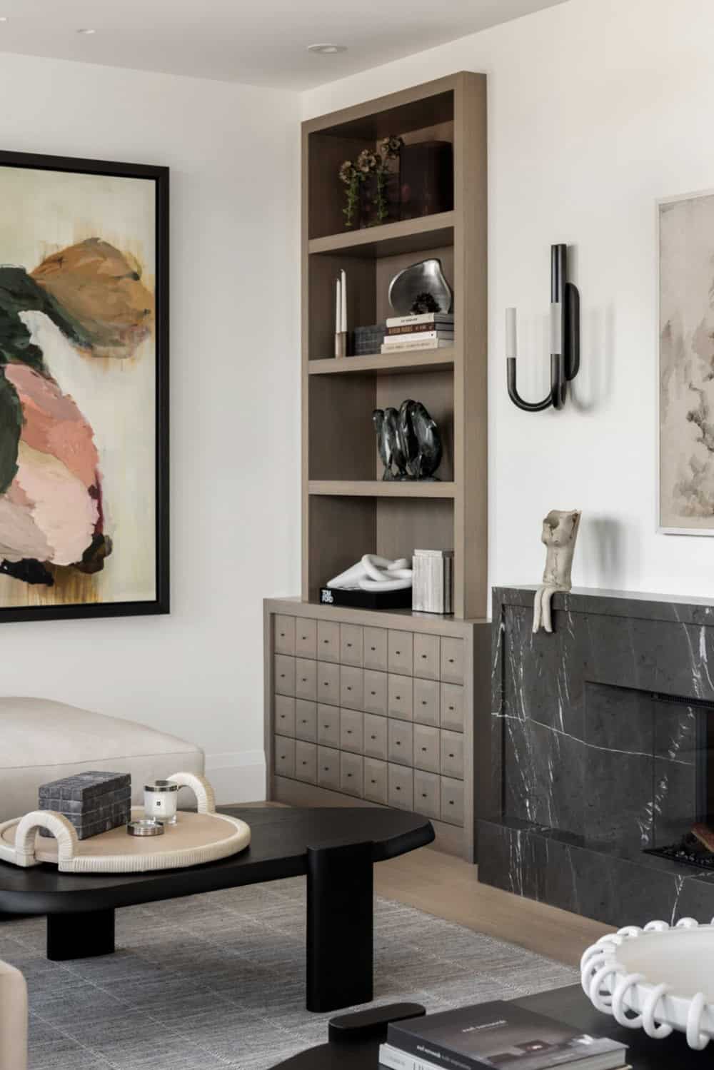 Built-in bookshelf with black marble fireplace and abstract painting