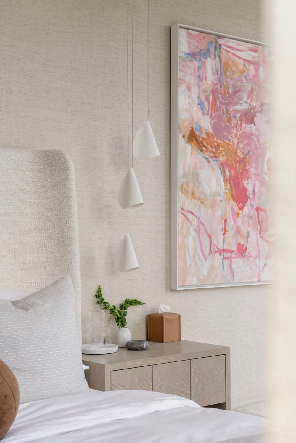 Bedroom with pink abstract art and cone pendant lighting over nightstand