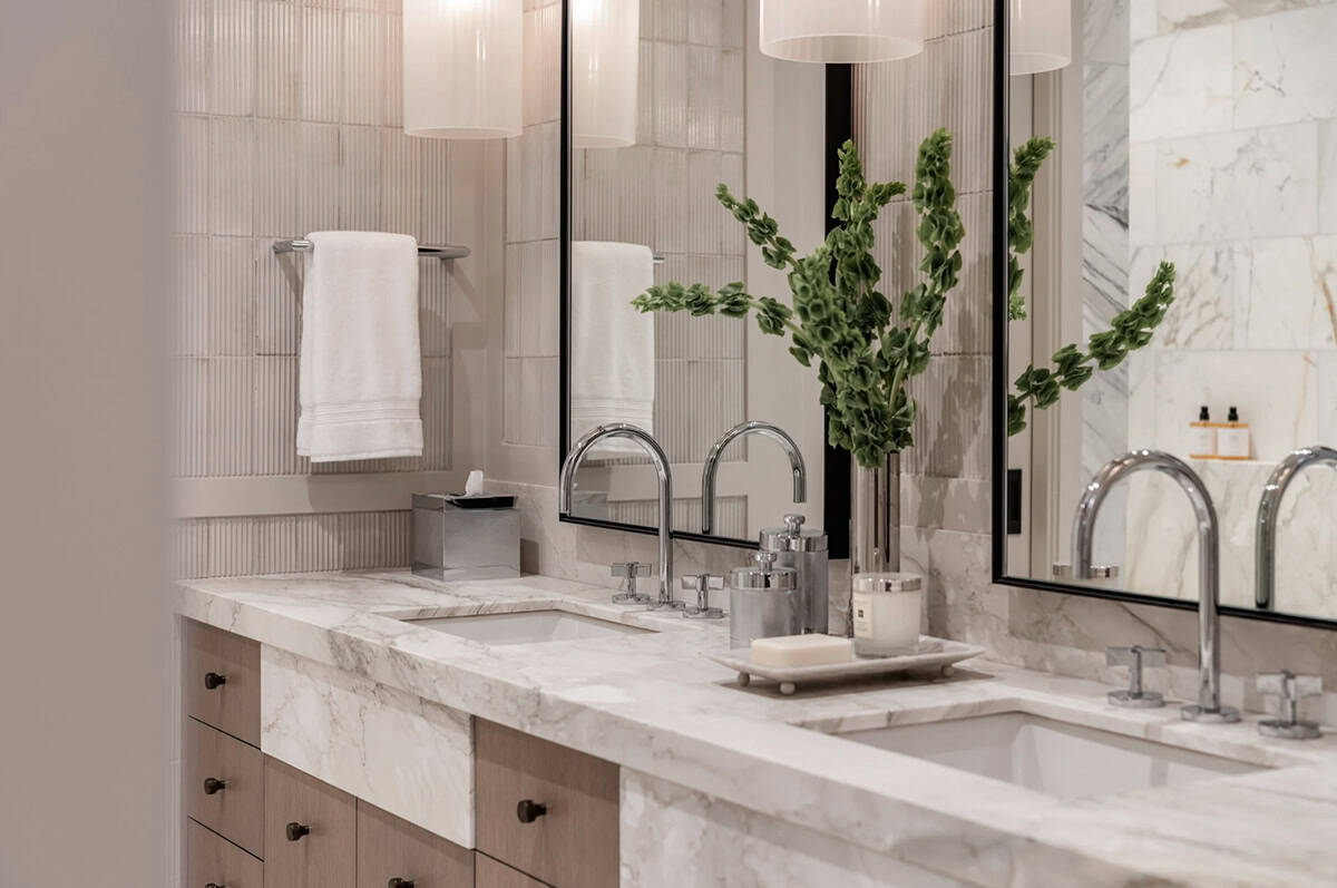 Marble vanity detail with brass fixtures and greenery