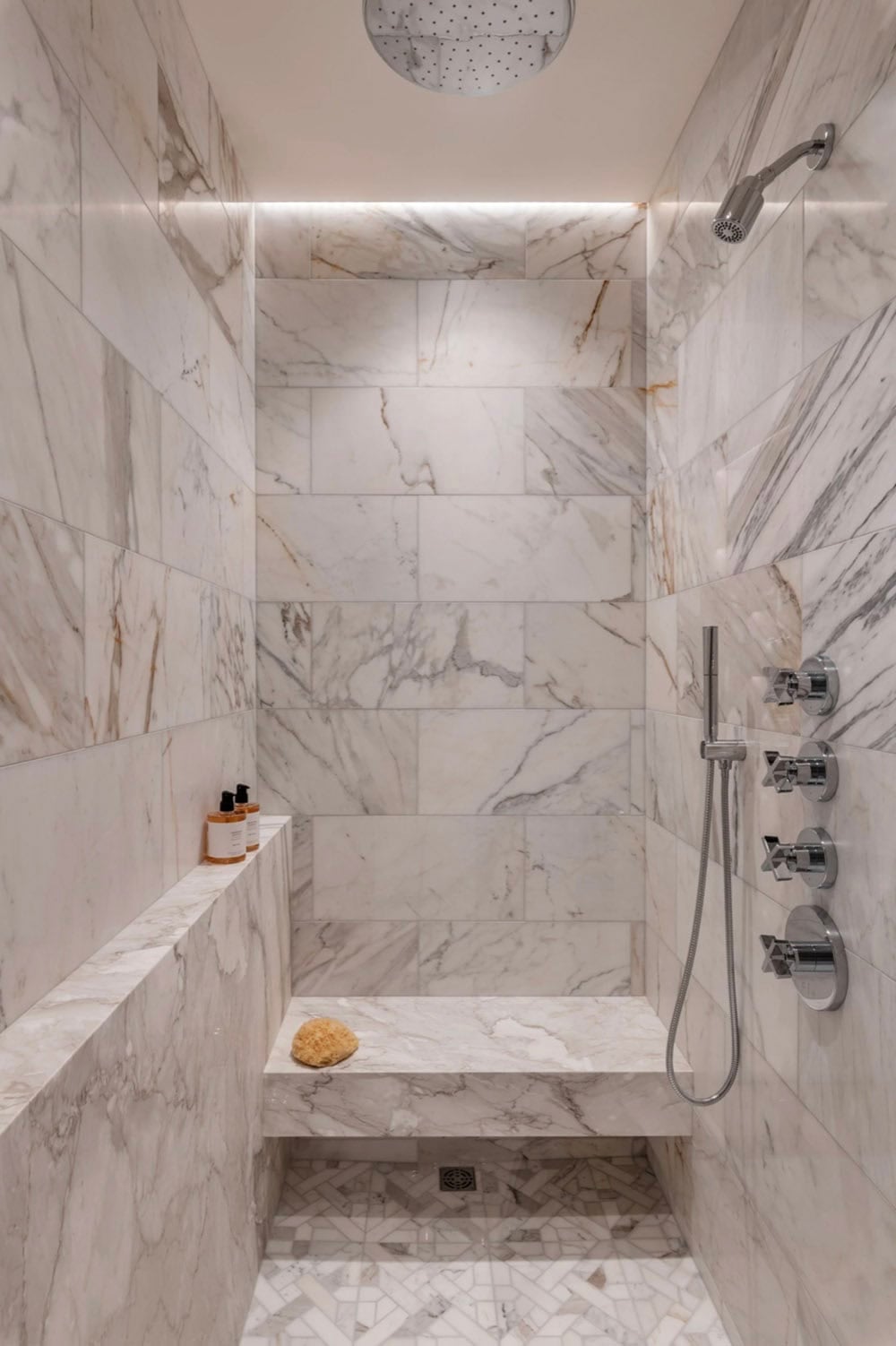 Marble walk-in shower with rainfall showerhead and bench seat