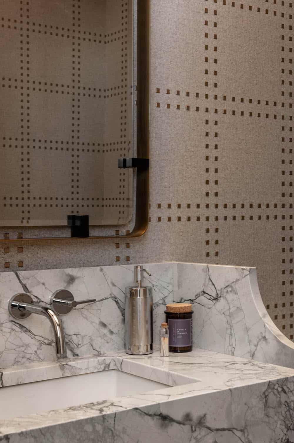 Powder room vanity detail with marble backsplash and soap dispenser