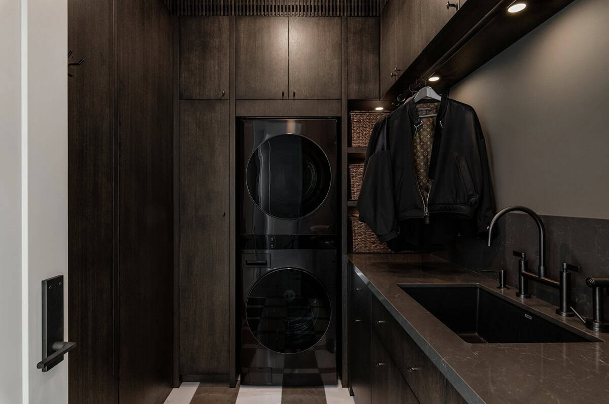 Laundry room with stacked washer dryer and dark cabinetry