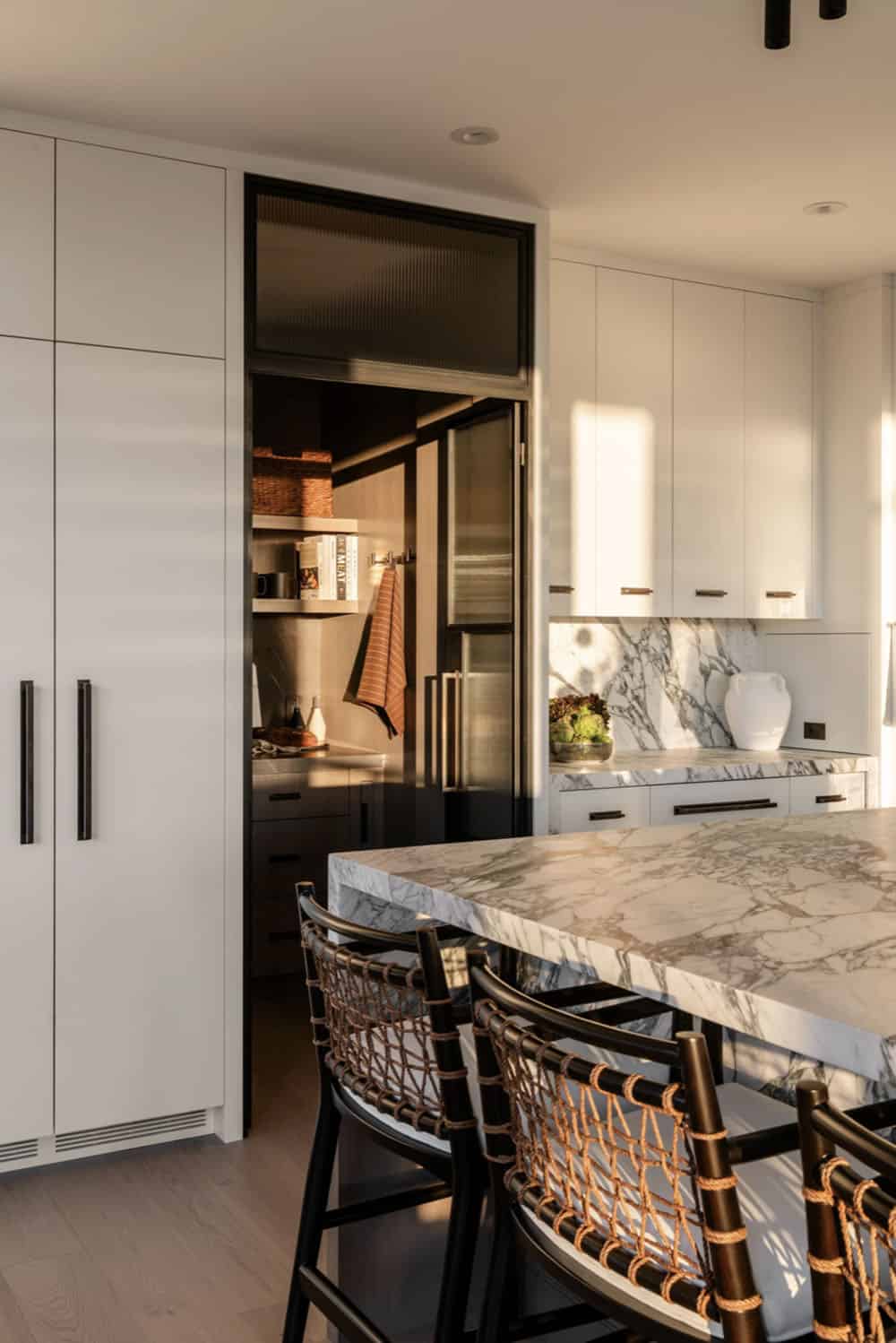 Kitchen island with pantry entrance and white cabinetry