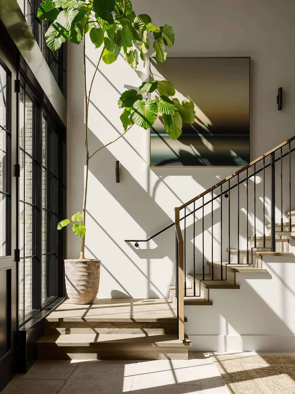 Sleek entryway featuring floating staircase and floor to ceiling windows