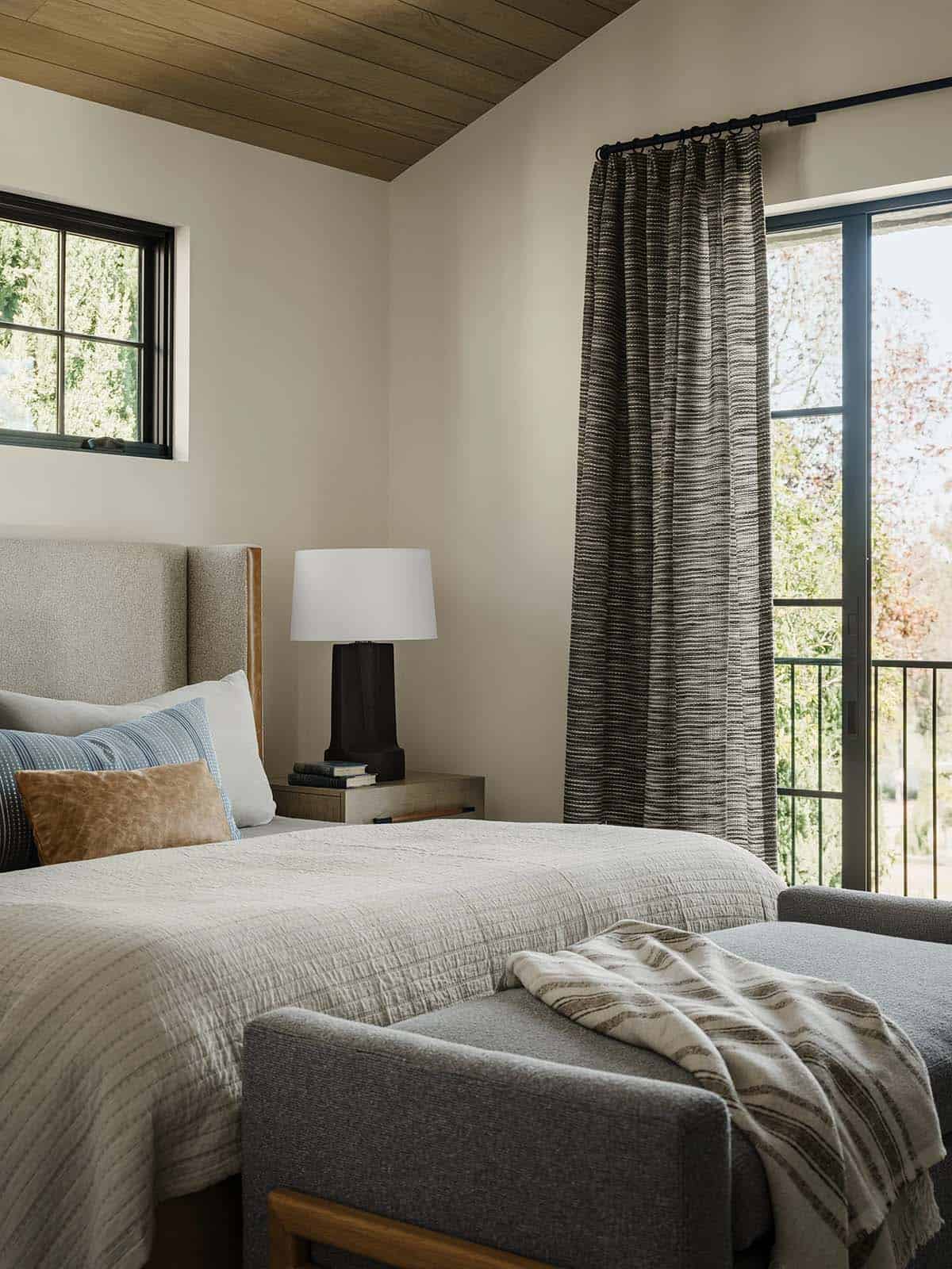 Guest bedroom with a bed and upholstered bench with a sliding glass door and private balcony