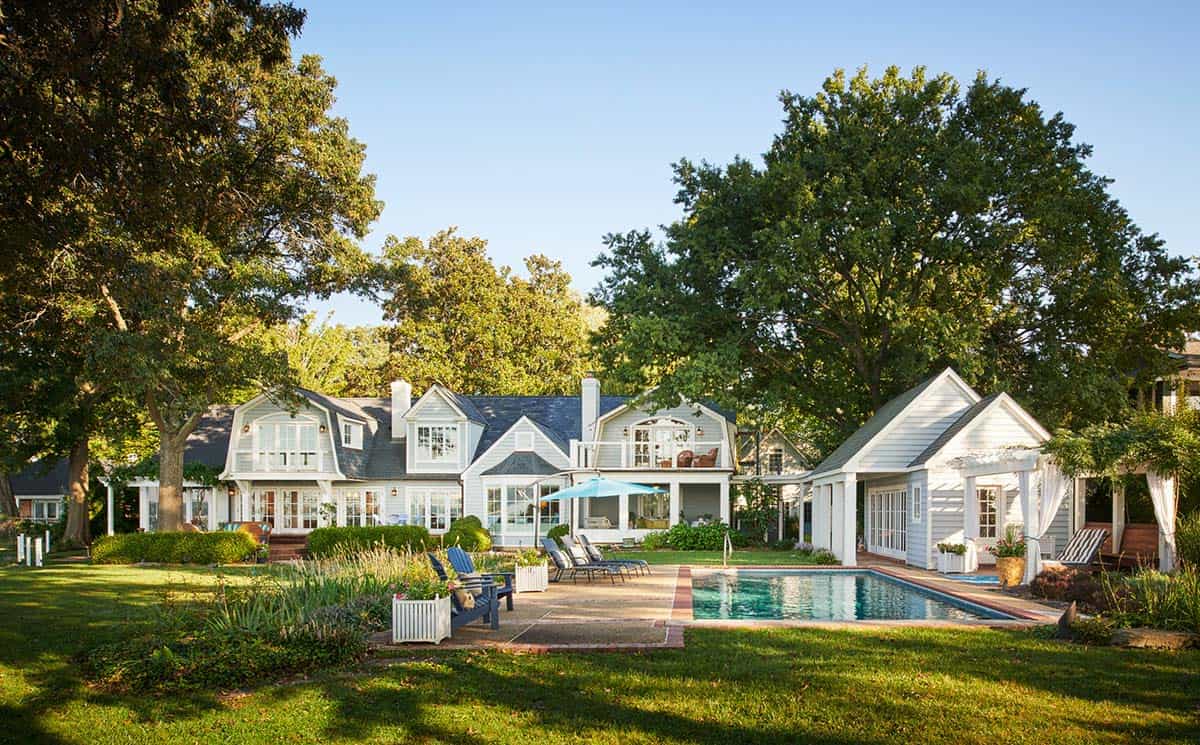 Back exterior of a beach-style home with pool, patio, and lush lawn