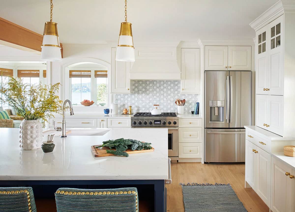 White kitchen with brass pendant lights and marble hexagon backsplash