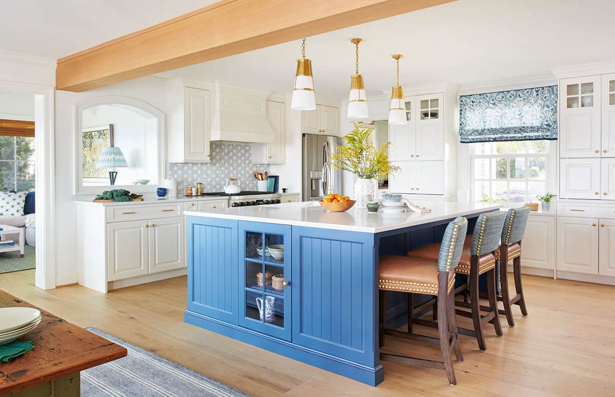 Kitchen island in blue with leather counter stools and brass pendants