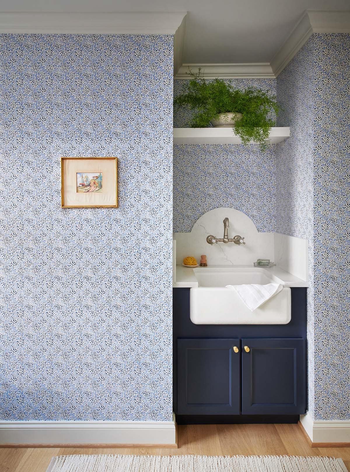 Utility sink nook with blue floral wallpaper and navy cabinet