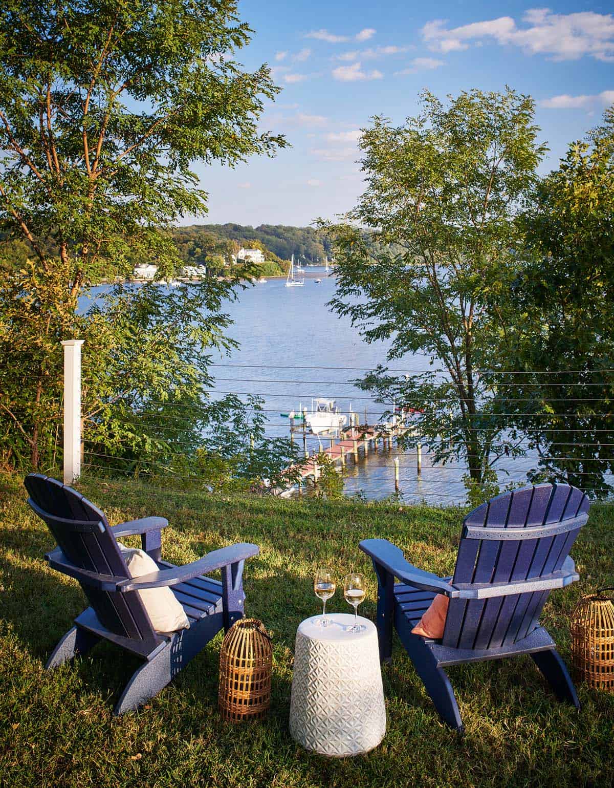 Two Adirondack chairs overlooking the river and dock at sunset