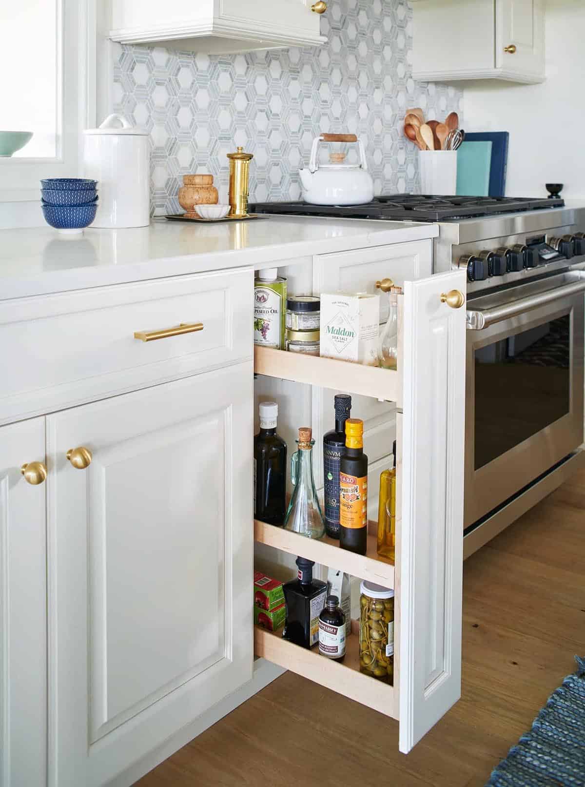 Pull-out pantry drawer with olive oils and pantry staples beside the range