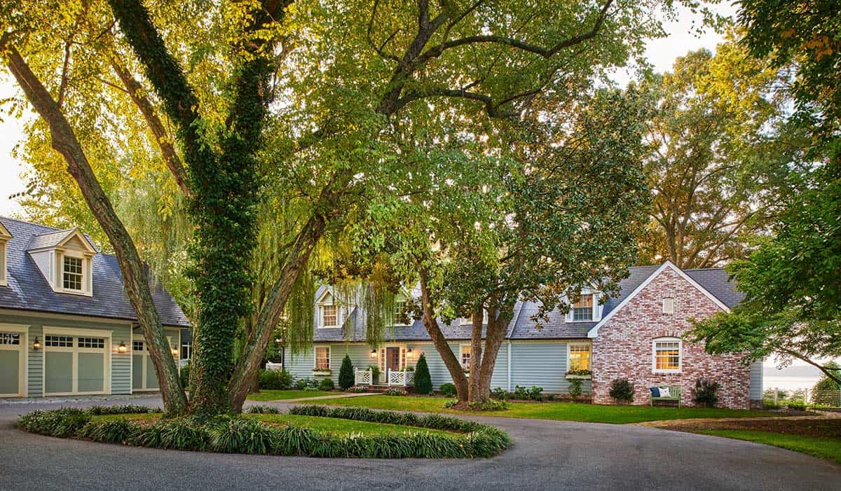 Front driveway view of the home with weeping willow and brick chimney