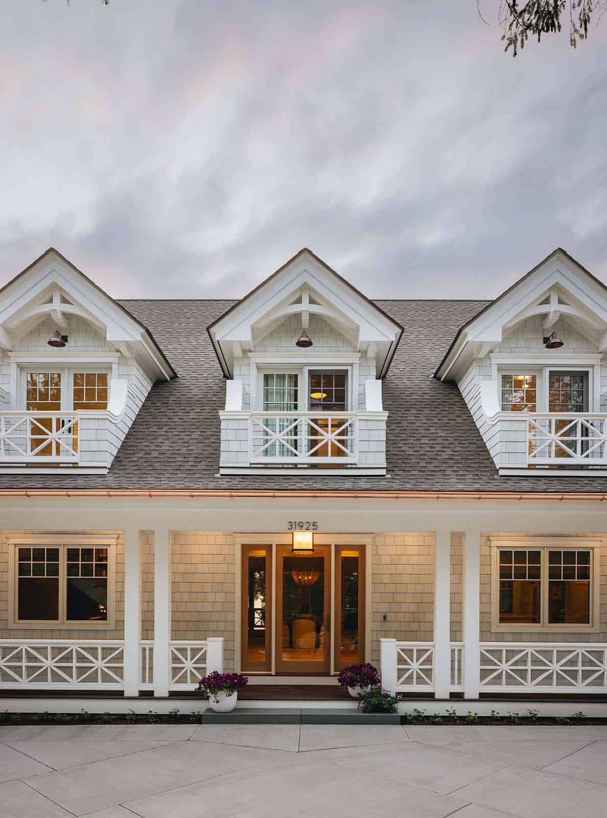 Front facade with three matching dormers, wraparound porch, and wood front door