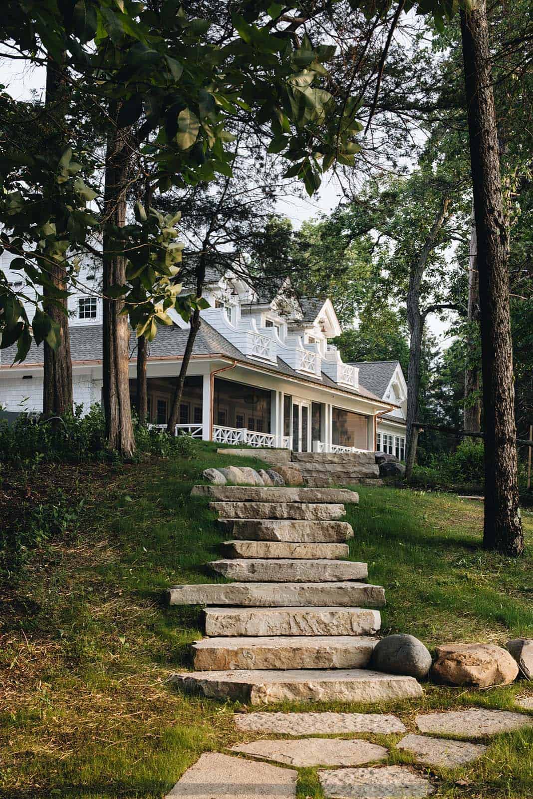 Stone steps leading up through wooded lawn to the lake house's screened porch