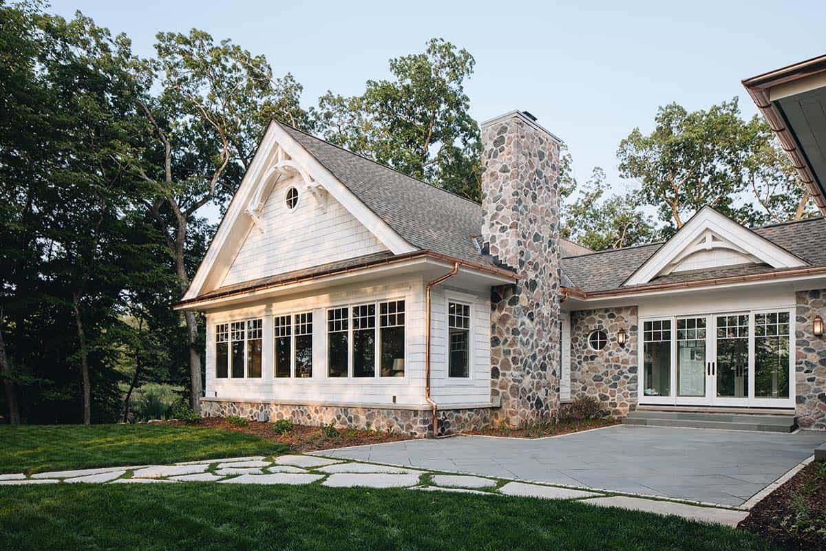 Side exterior view of stone chimney, gabled roof, and copper gutters