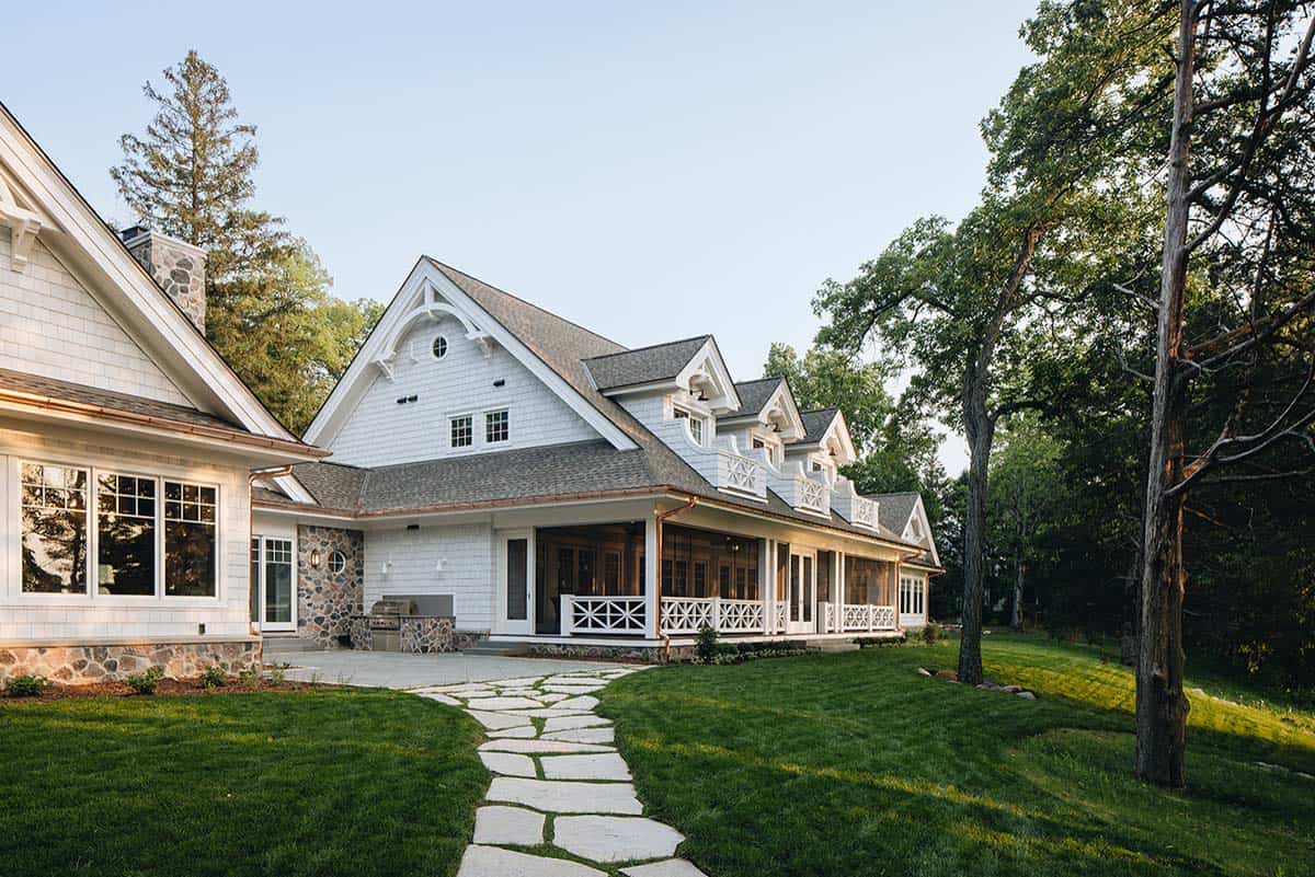 Rear exterior view of house with wraparound porch and stone path across lawn