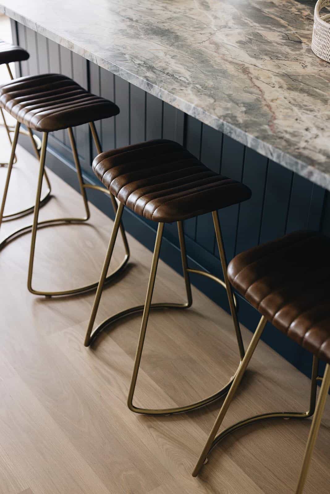 Leather and brass counter stools at marble bar counter