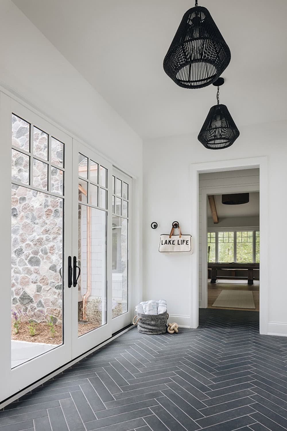Mudroom with black woven pendant lights and herringbone tile floor