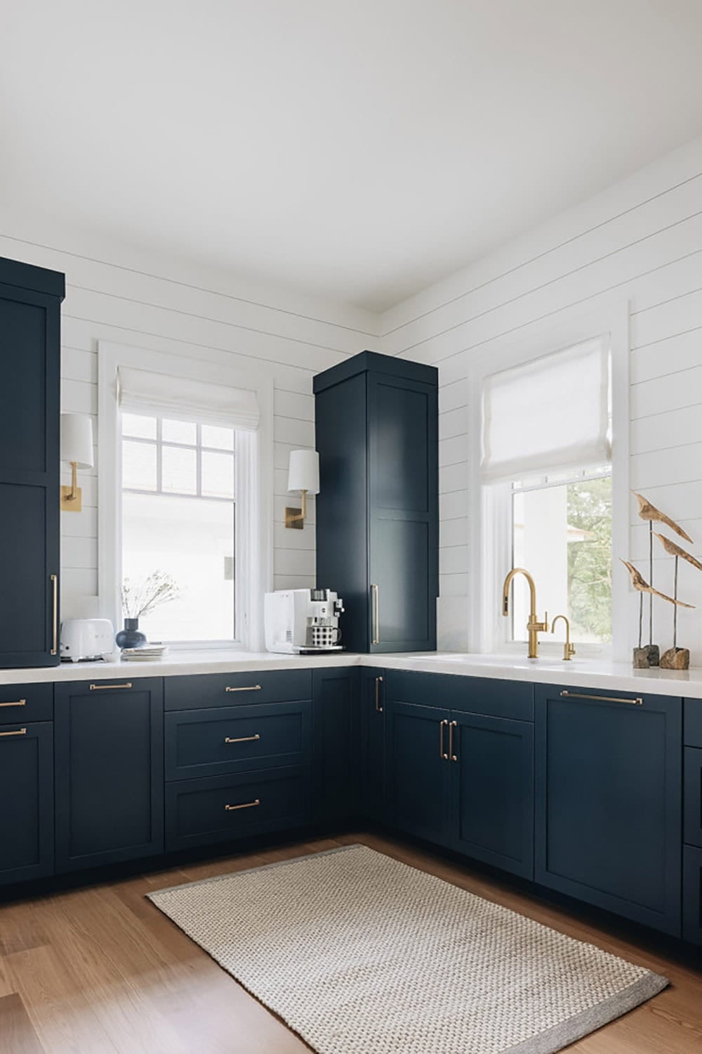 Kitchen corner with navy cabinetry, brass fixtures, and white countertops