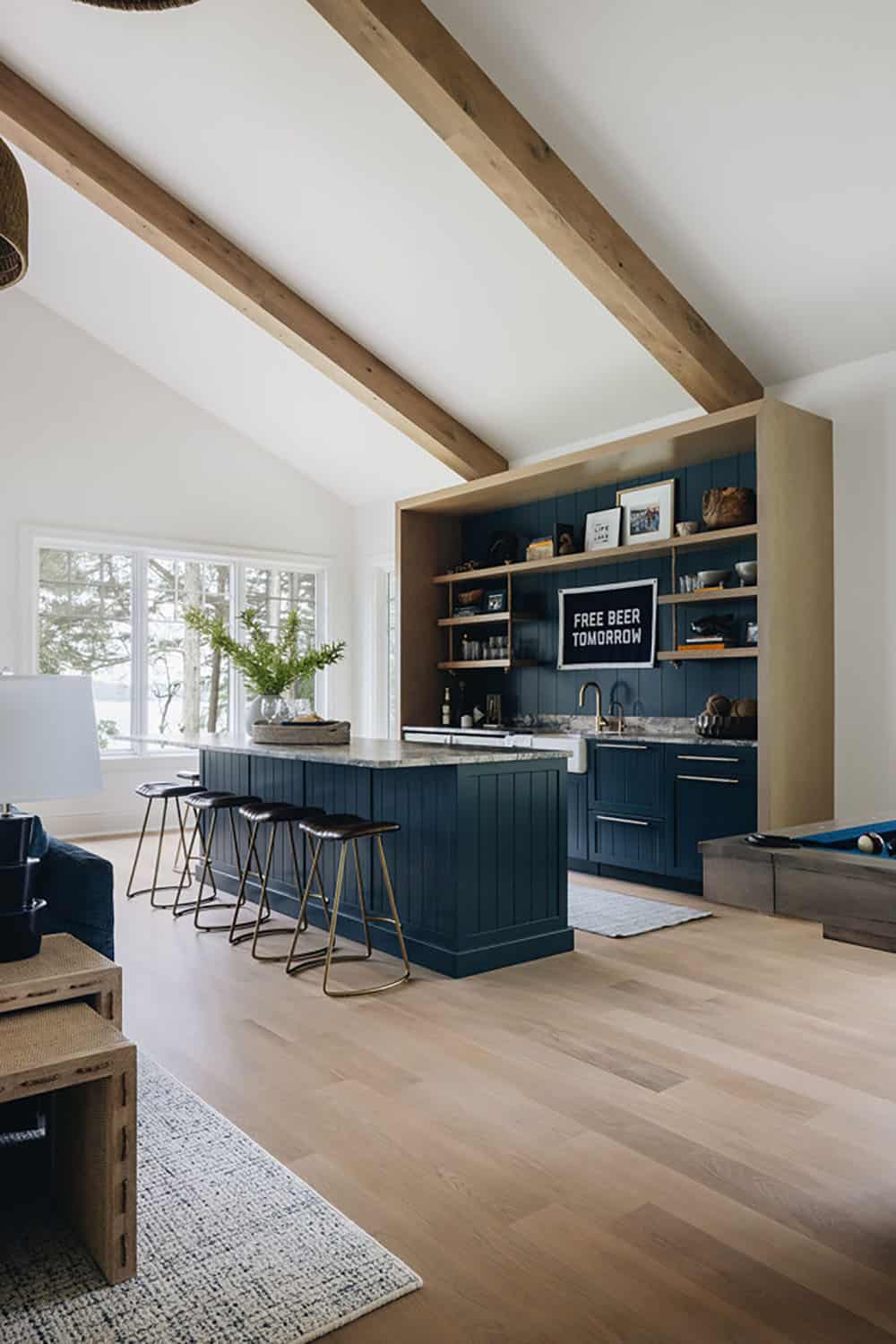 Navy game room bar with brass stools, marble counter, and pool table view