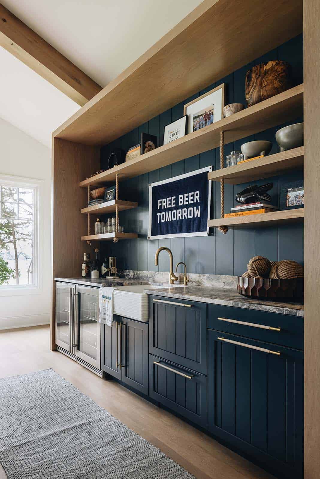 Close-up of navy shiplap wet bar with rope-hung shelves and gold fixtures