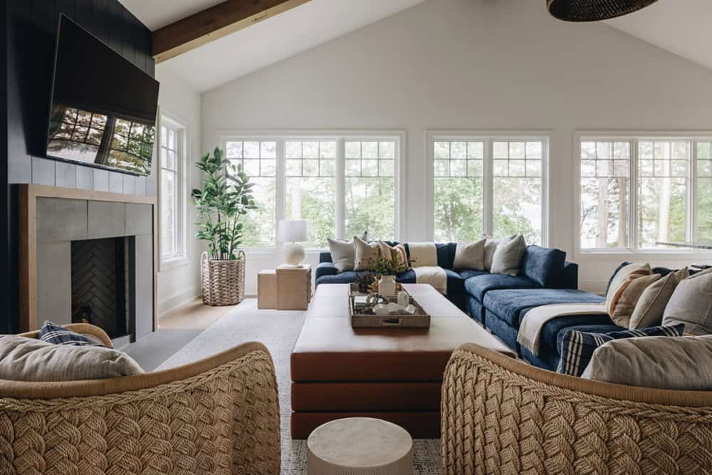 Living room with woven armchairs, fireplace, and TV facing lake-view windows