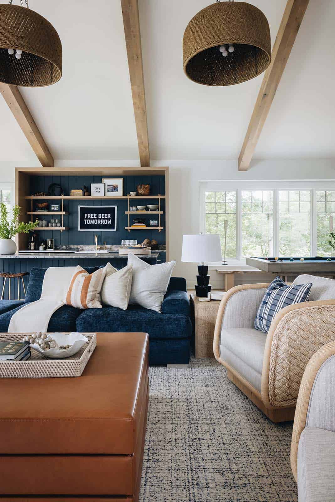 Seating area with navy sofa, woven chairs, and wicker pendant lights