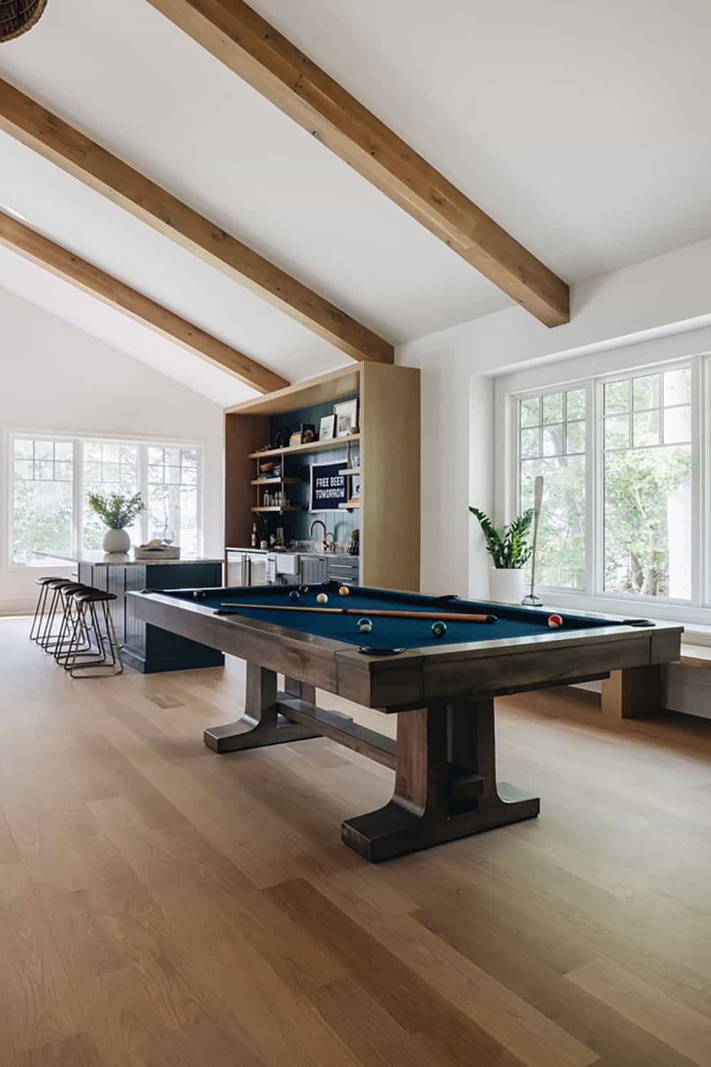 Game room with pool table, wood beams, and bar area in the background