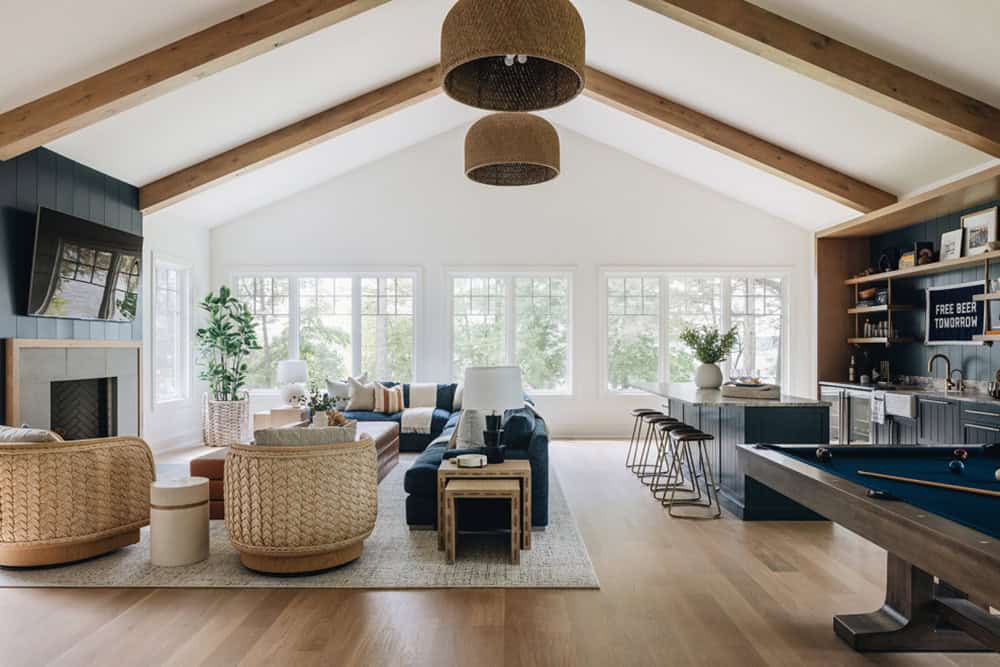 Wide view of living room, bar, and pool table under vaulted wood-beam ceiling