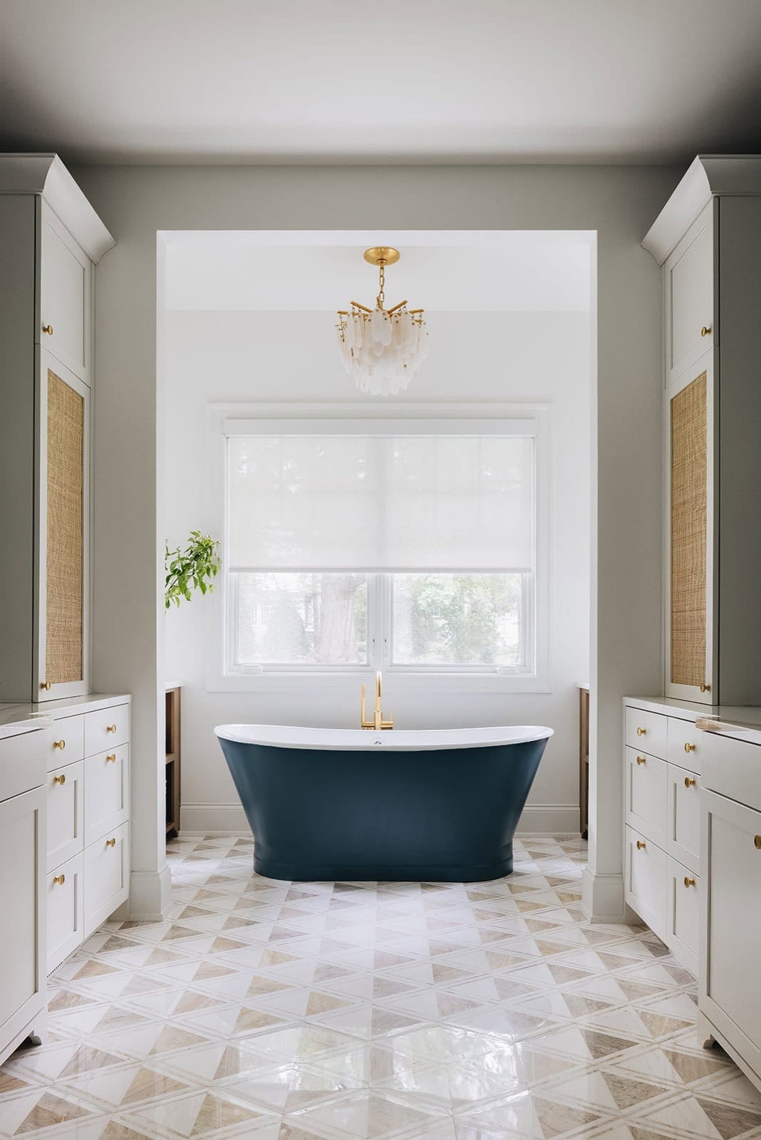 Primary bathroom with navy soaking tub framed by an archway and patterned floor