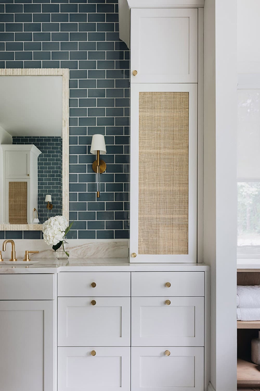 Bathroom vanity with blue subway tile, rattan cabinet panel, and brass hardware