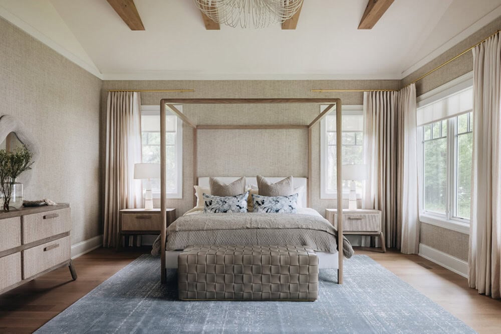 Primary bedroom with canopy bed, blue rug, and matching nightstand lamps