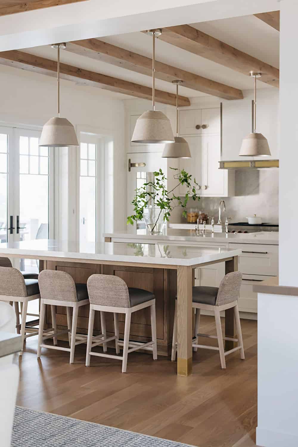 Kitchen island with woven counter stools and pendant lights over dual islands