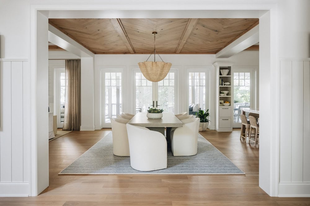Dining room with wood plank ceiling, white curved chairs, and pendant light