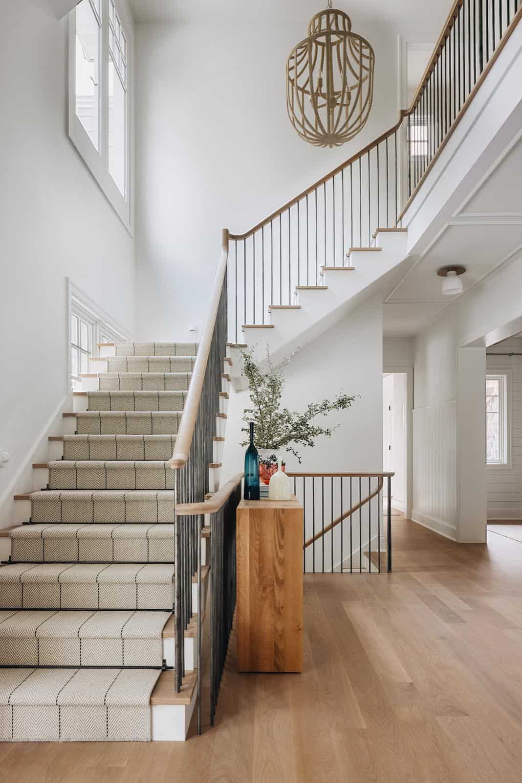 Staircase with striped runner, rope pendant light, and live-edge console table
