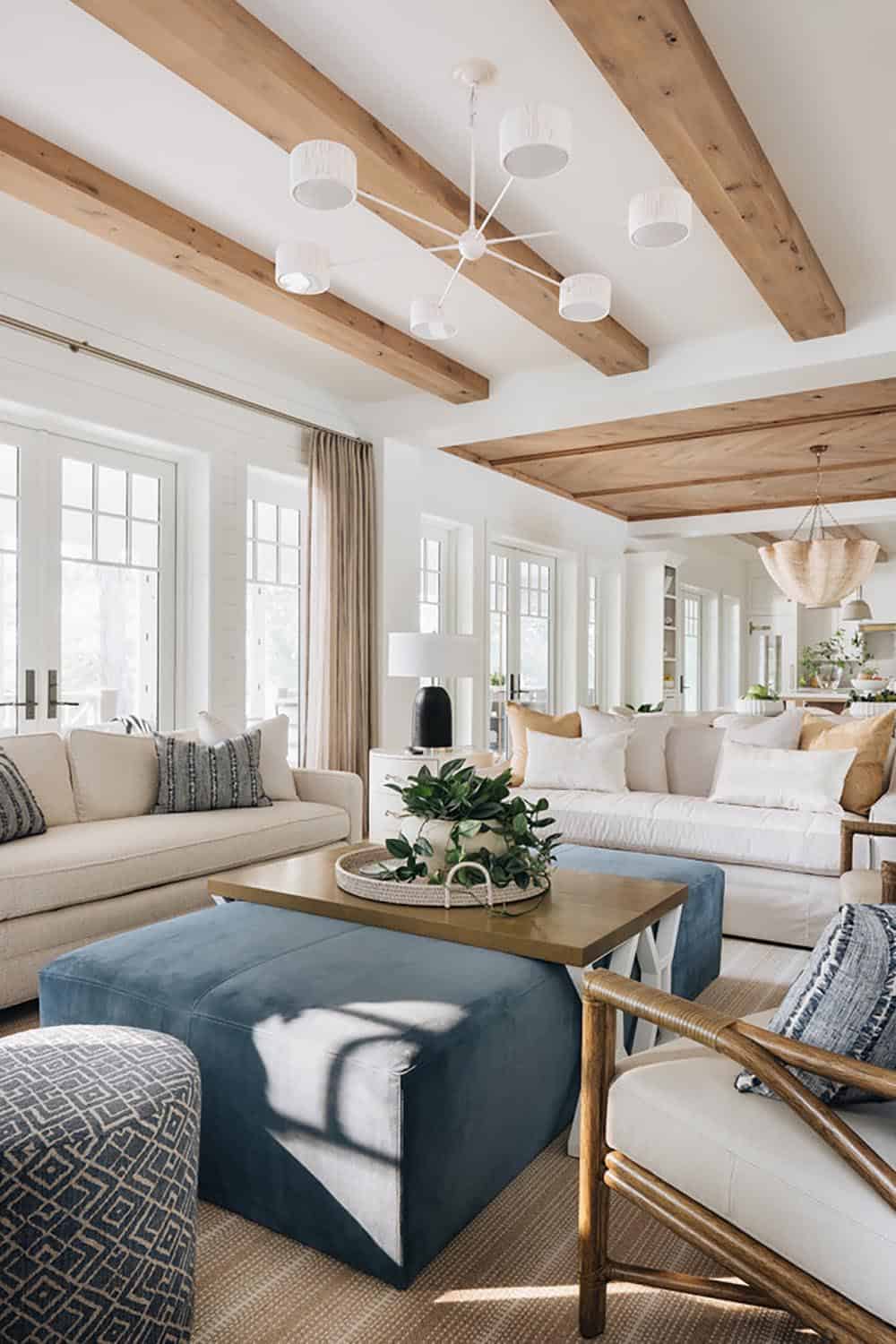 Living room with beamed ceiling, blue ottomans, and view into dining area