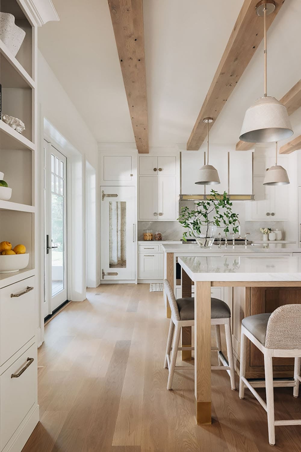 White kitchen hallway with wood beams, island seating, and pantry shelving