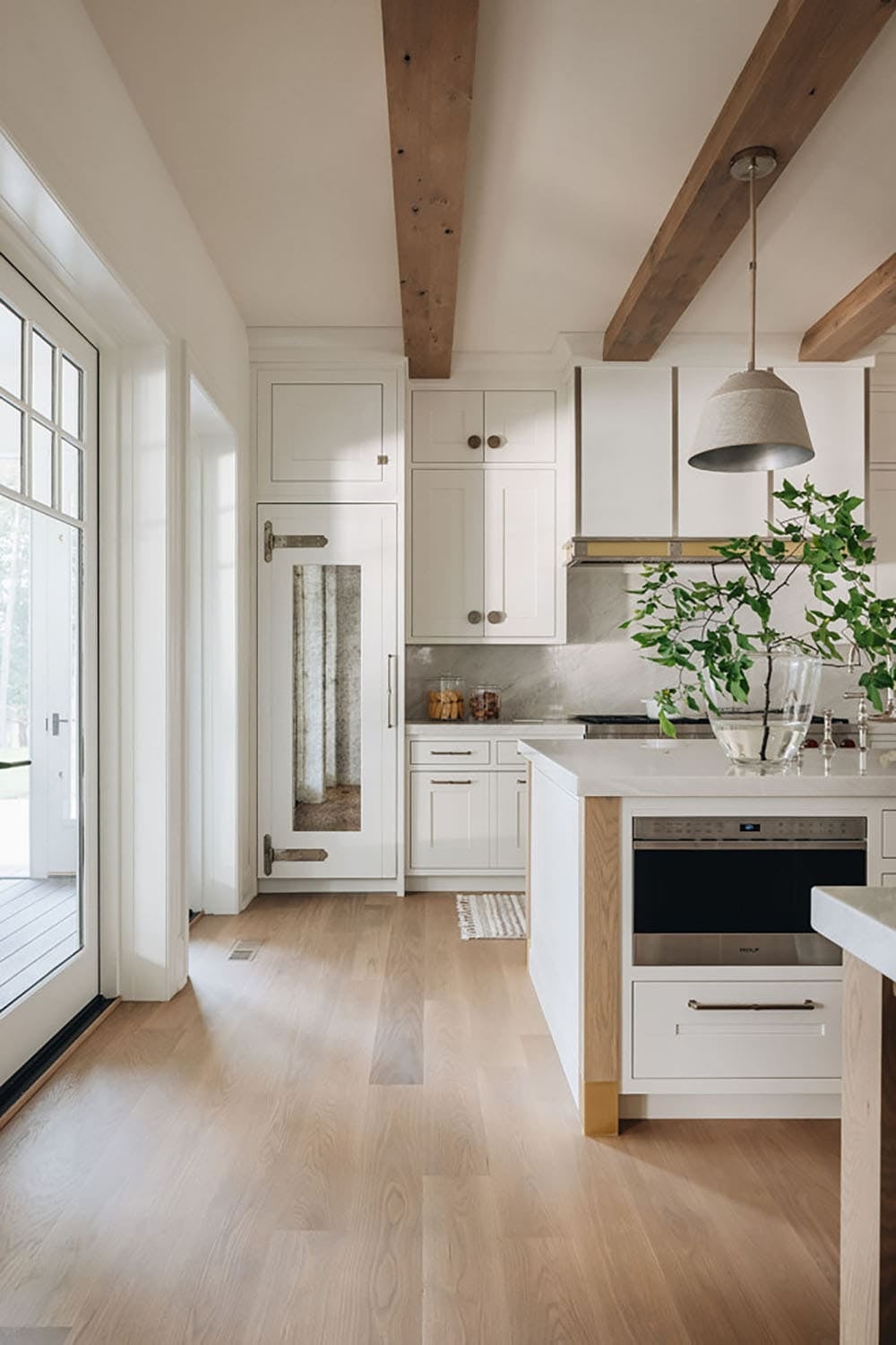 White kitchen with antiqued mirror pantry door and wood beam ceiling