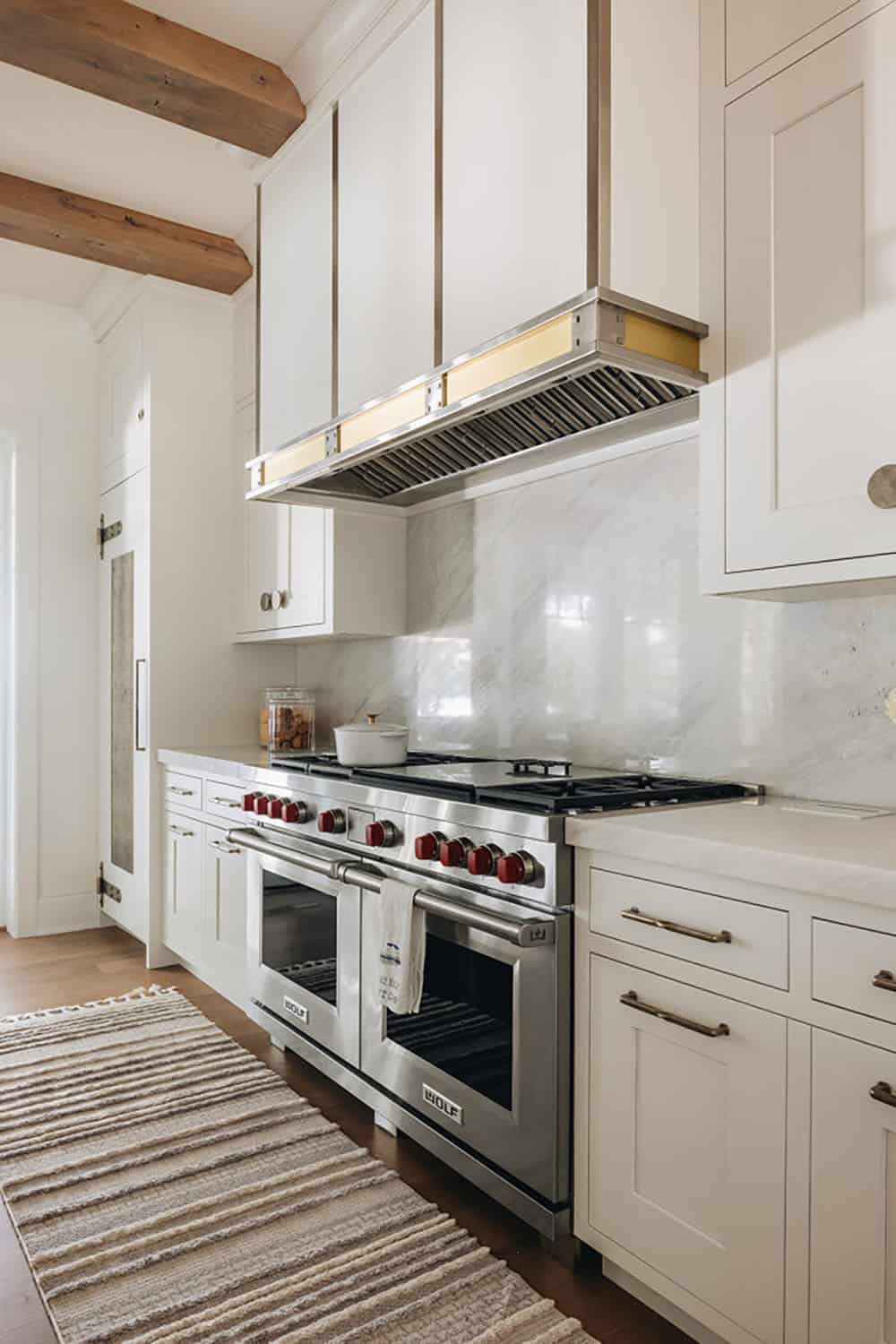 Stainless steel range with red knobs beneath marble backsplash