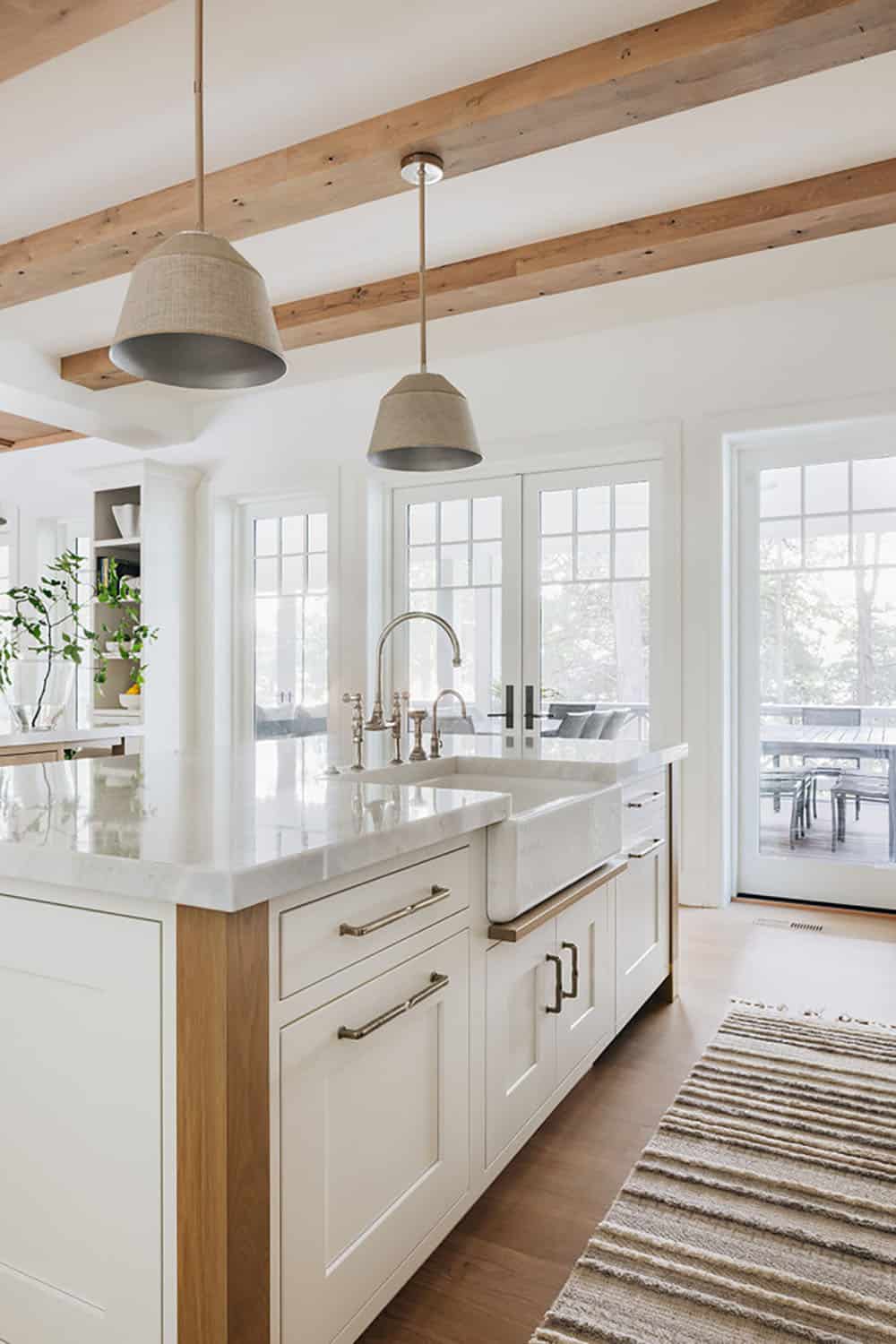 Kitchen island with farmhouse sink, brass fixtures, and striped runner